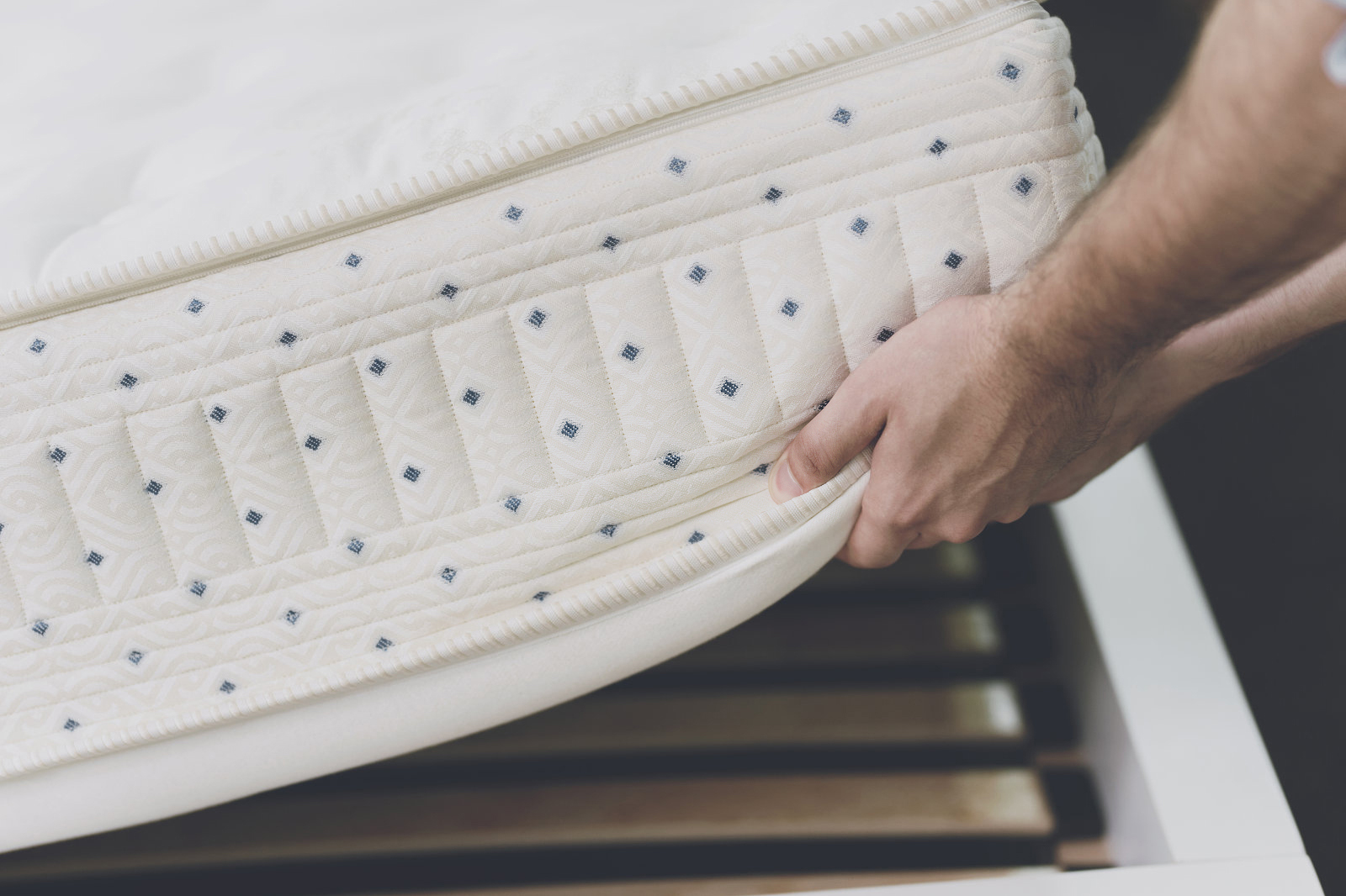 Close up. The man lifted the mattress to look at the bed frame on which he lay. He also inspects the mattress