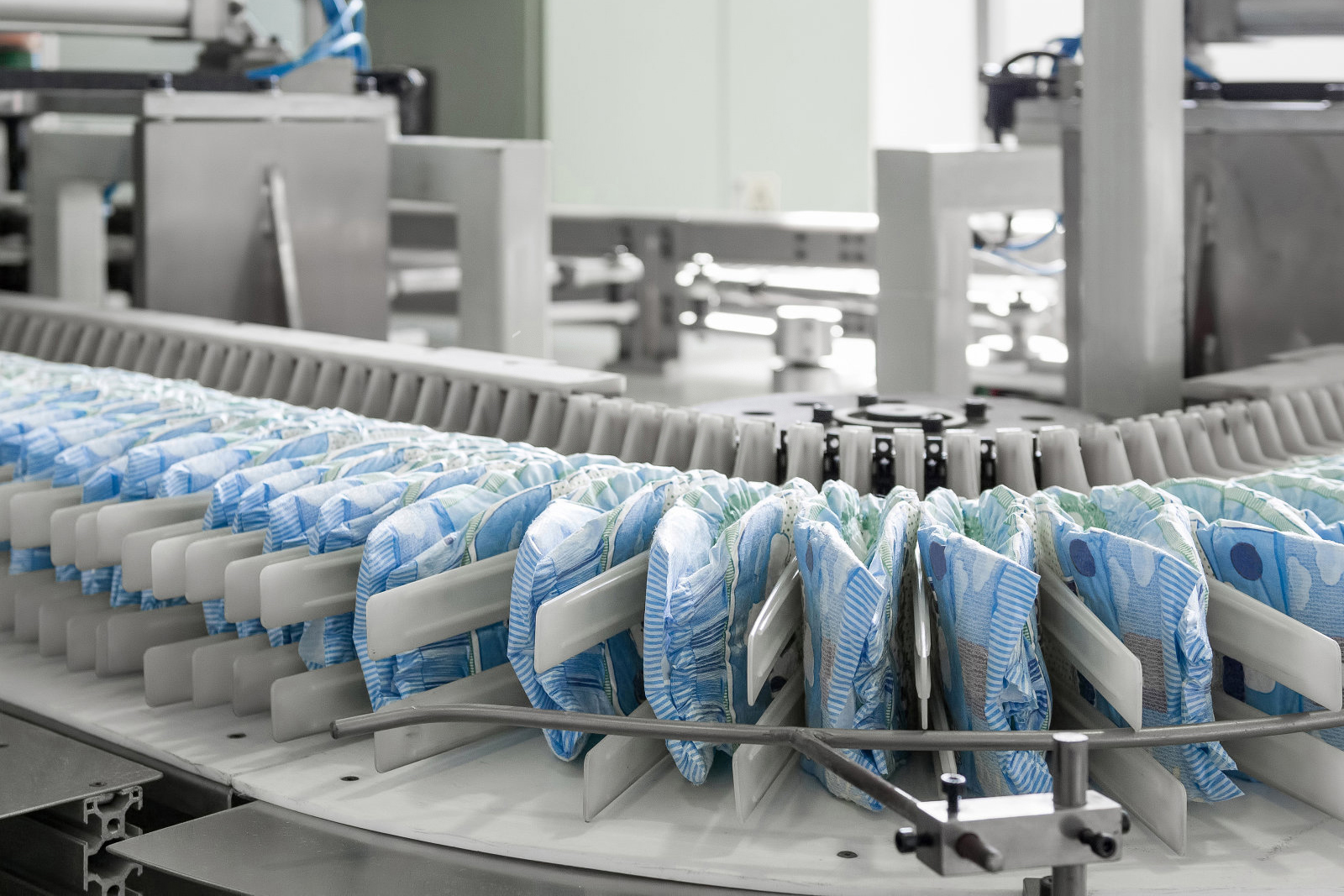 diapers on a conveyor belt closeup. factory and equipment for the production of pampers